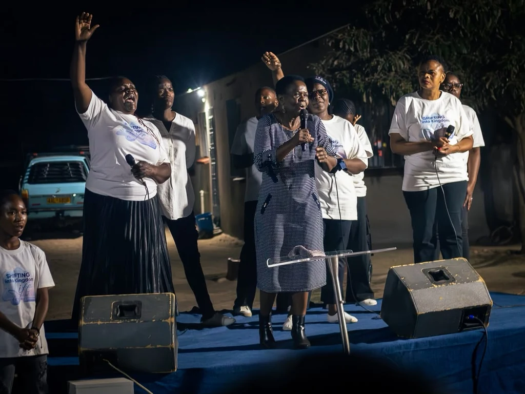 Church members singing and speaking at an outdoor evening gathering