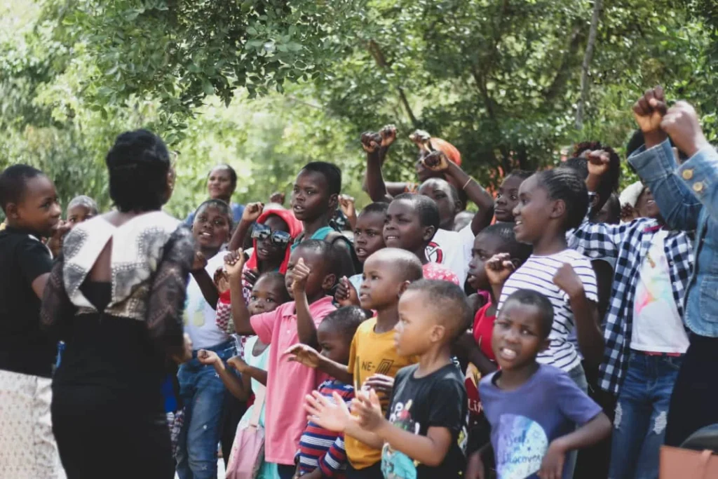 Children singing together outdoors with members of the church